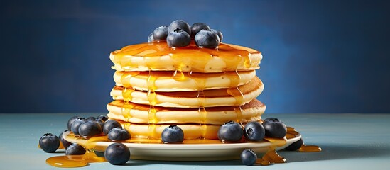 Fototapete - Blueberry pancakes stacked high, topped with syrup, served with fresh orange juice on the side. with copy space image. Place for adding text or design