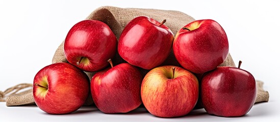 Multiple ripe red apples arranged on a wooden tabletop, some apples in a burlap sack, against a white background. with copy space image. Place for adding text or design
