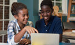 © kmlPhoto - Two young people are sitting at a table looking at a laptop