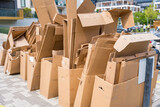 Pile of cardboard boxes ready for recycling outside a building.