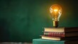 © Vodkaz - Illuminated Path A single light bulb illuminates a stack of books, casting a warm glow on a serene green background, representing the power of knowledge to bring light and understanding