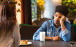 © Prostock-studio - Two African American teenagers are seated at a cafe table. One appears deep in thought while the other is speaking. There is a milkshake and a plate with a piece of cake on the table