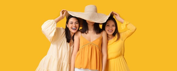 Poster - Beautiful young women with big beach hat on yellow background