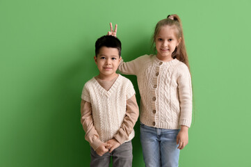 Wall Mural - Cute little children in knitted sweaters on green background