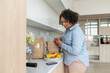 © Basil Pind/Stocksy - Woman Checking Smartphone in Kitchen