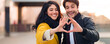 © Prostock-studio - Romantic couple making heart shape with hands, walking in autumn day in city center
