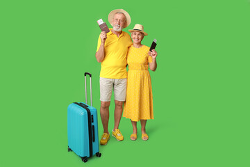 Poster - Mature couple of travelers with passports and suitcase on green background