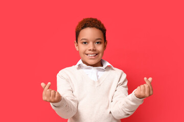 Wall Mural - Cute little African-American boy showing heart gesture on red background. Valentine's day celebration