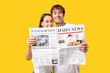 © Pixel-Shot - Young couple with newspaper on yellow background