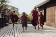 © Heng Yu/Stocksy - Monks playfully running on wooden deck