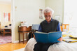 © Diego Martin/Stocksy - Senior retired man reading book in bed at home