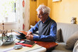 © Diego Martin/Stocksy - Senior man at home working on his digital tablet on the sofa