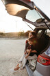 © Irina Polonina/Stocksy - Mother and daughter in car trunk at sunset