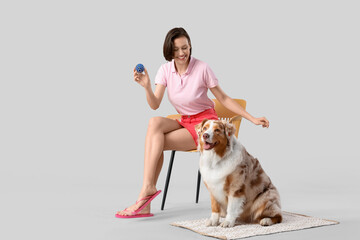 Poster - Pretty young woman playing with cute Australian Shepherd dog on grey background