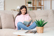 © Pixel-Shot - Beautiful young woman reading book and sitting on couch at home