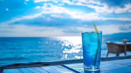 Canvas Print - Blue drink on table with sea and sky view.