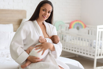 Sticker - Beautiful young happy woman in bathrobe breastfeeding her baby at home