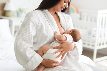 Sticker - Beautiful young happy woman in bathrobe breastfeeding her baby at home