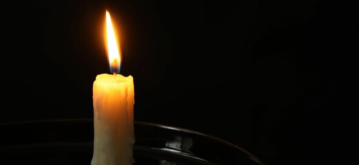 Wall Mural - One burning church candle on black background, closeup. Space for text