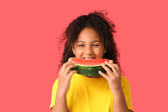 Cute African-American girl eating slice of sweet watermelon on red background