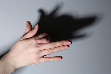 Wall Mural - Shadow puppet. Woman making hand gesture like dog on grey background, closeup