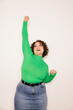 © VICTOR TORRES/Stocksy - Joyful curvy woman in green top celebrating with raised arm