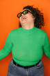 © VICTOR TORRES/Stocksy - Joyful curvy woman in green laughing against orange background