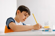 © VICTOR TORRES/Stocksy - Young boy focused on writing in his notebook at home