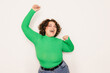 © VICTOR TORRES/Stocksy - Cheerful curvy woman celebrating in a vibrant green sweater