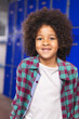 © wavebreak3 - Biracial student smiling in front of blue background school lockers