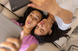 © Wavebreak Media - Two young biracial sisters are taking selfie together while lying on a couch, at home
