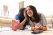 © Wavebreak Media - Two young biracial friends are lying on floor, sharing secret and smiling, at home