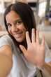 © Wavebreak Media - Biracial young woman smiling and waving at camera, at home