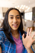 © Wavebreak Media - Biracial young girl smiling and waving at camera, at home