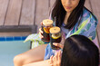 © Wavebreak Media - Two biracial young sisters enjoying drinks together by pool, at home