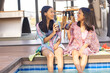 © Wavebreak Media - Two biracial young sisters are sitting by pool, enjoying drinks and smiling, at home