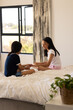 © Wavebreak Media - Two young biracial sisters are sitting on bed, enjoying each other's company, at home