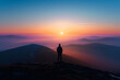 © Ateeq - A silhouette of a person standing on a mountain top at dawn, surrounded by the serene glow of the sunrise.
