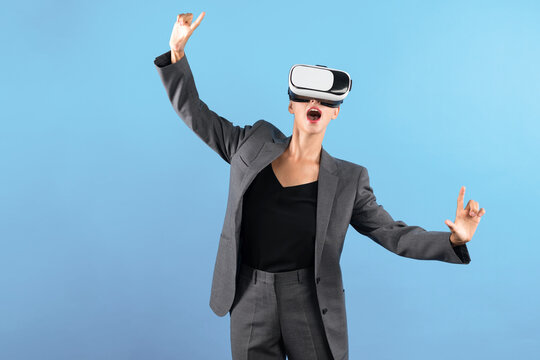 Caucasian business woman excited to explore visual reality world while standing and pointing at data. Skilled project manager wearing VR goggle and suit. Technology innovation concept. Contraption.