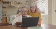 © Charlize Davids/peopleimages.com - Senior couple, home and laptop for internet research with for retirement and social media update. Interracial marriage, old man and woman with computer in kitchen for video call app and virtual chat