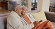 © Charlize Davids/peopleimages.com - Senior couple, home and remote for watching tv with retirement and streaming movie together. Interracial marriage, old man and woman on couch with change channel or click for online series with relax