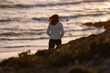 © Cavan - Woman walking along the beach at sunset in Sagres, Algarve, Portugal