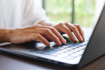 Wall Mural - closeup image of a woman hands working and typing on laptop computer keyboard