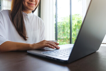 Wall Mural - closeup image of a woman working and typing on laptop computer keyboard