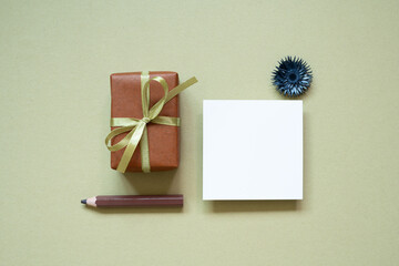 Wall Mural - Brown gift box, colored pencil, memo pad, dry flower on khaki background. top view