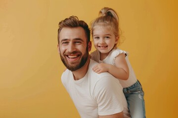 Wall Mural - Laughable bearded man in casual clothing pose with baby girl. Father and daughter play together on a yellow background. Parents and children. Hugging and looking at each other.