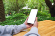 © Farknot Architect - Mockup image of a woman holding mobile phone with blank white desktop screen in the outdoors