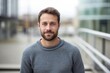 © CogniLens - Portrait of a grinning man in his 30s dressed in a comfy fleece pullover in modern cityscape background
