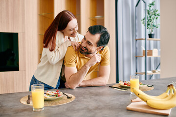 Wall Mural - A beautiful redhead woman and a bearded man enjoying a peaceful breakfast together in their modern kitchen.