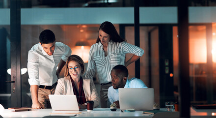 Fototapete - Collaboration, team diversity and office at night for deadline, strategy and explanation with laptop. Female leader, group and workshop for learning, growth and development in workplace in evening